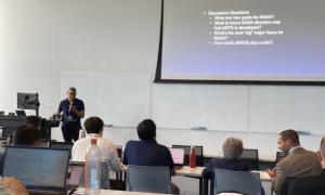 Meeting Room:  Speakers in front of attendees, slides behind speakers 